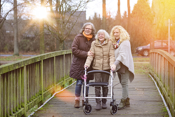 Frau mit Rollator und Begleitung